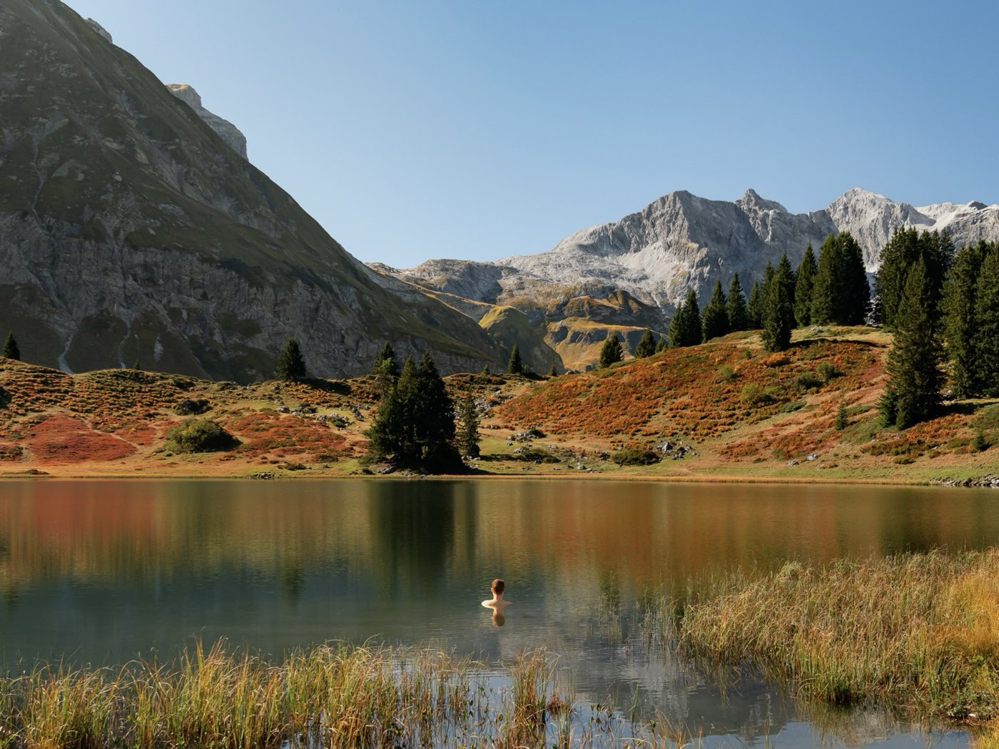 Swim in an alpine lake in autumn, rocky peaks behind